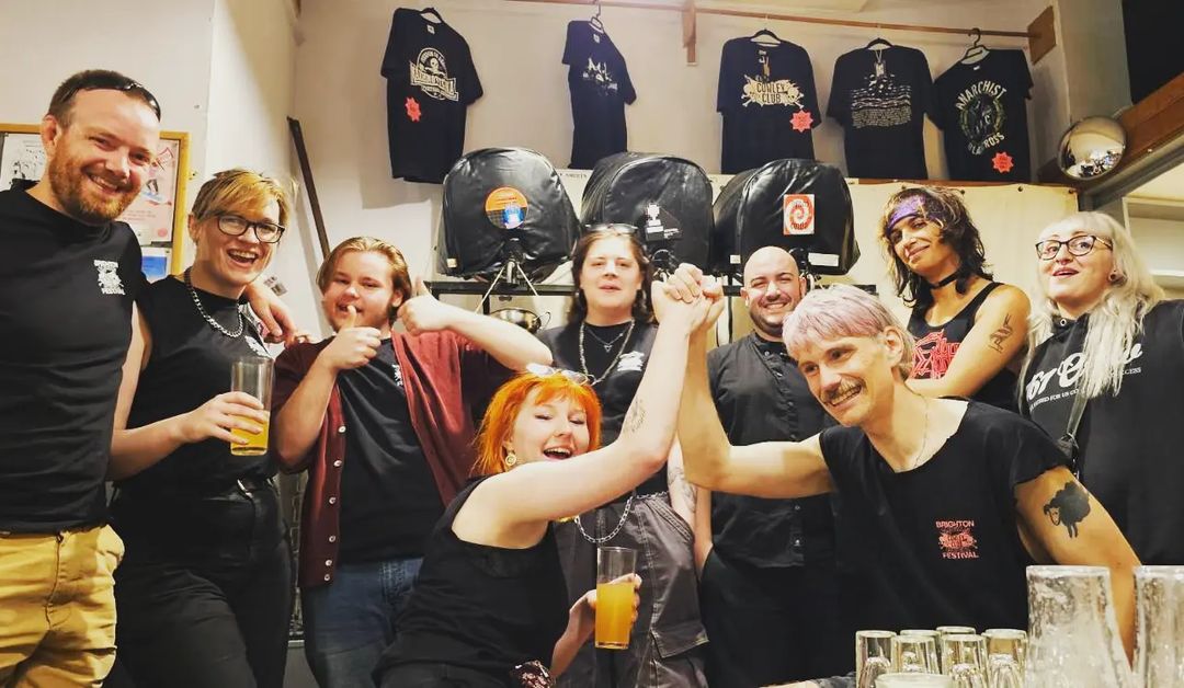 group of people laughing and smiling in front of beer casks